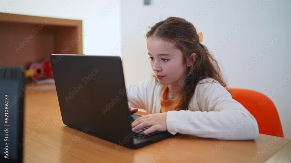 Young student does schoolwork on a laptop in a modern living room space Young student does schoolwork on a laptop in a modern living room space