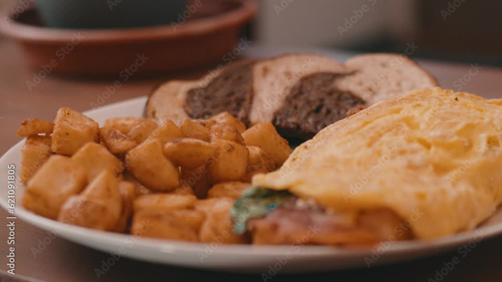 Egg Omelet, Homefries and Rye Toast on a White Plate on a wooden table in 4k Egg Omelet, Homefries and Rye Toast on a White Plate on a wooden table in 4k