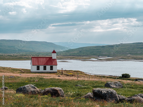 Small traditional, white, wooden church with red roof in the field. Church in Iceland.