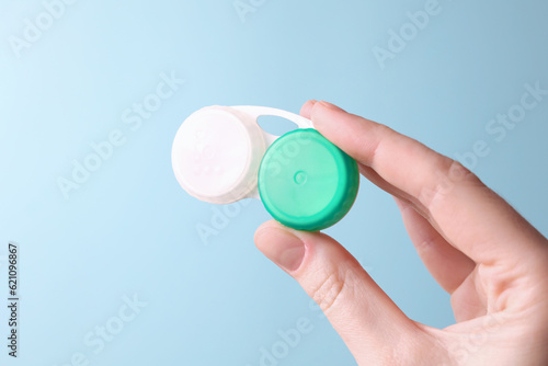 Contact lens container in hand on a colored background. Vision correction. 