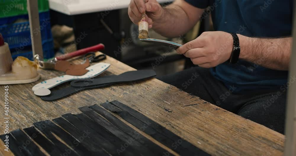Close-up shot, the hands of a man who glues parts of the insoles for shoes. Shoe production at a special handmade factory Close-up shot, the hands of a man who glues parts of the insoles for shoes. Shoe production at a special handmade factory