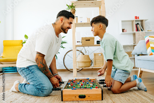 happy father and son smiling while playing table football together at home