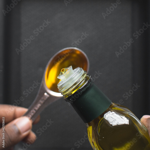 Pouring olive oil into a measuring spoon, measuring a tablespoon of oil