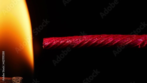 A macro shot of a burning fuse in front of a black background. Slow Motion.