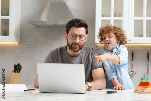 Man with laptop working remotely at home. Father and son at desk