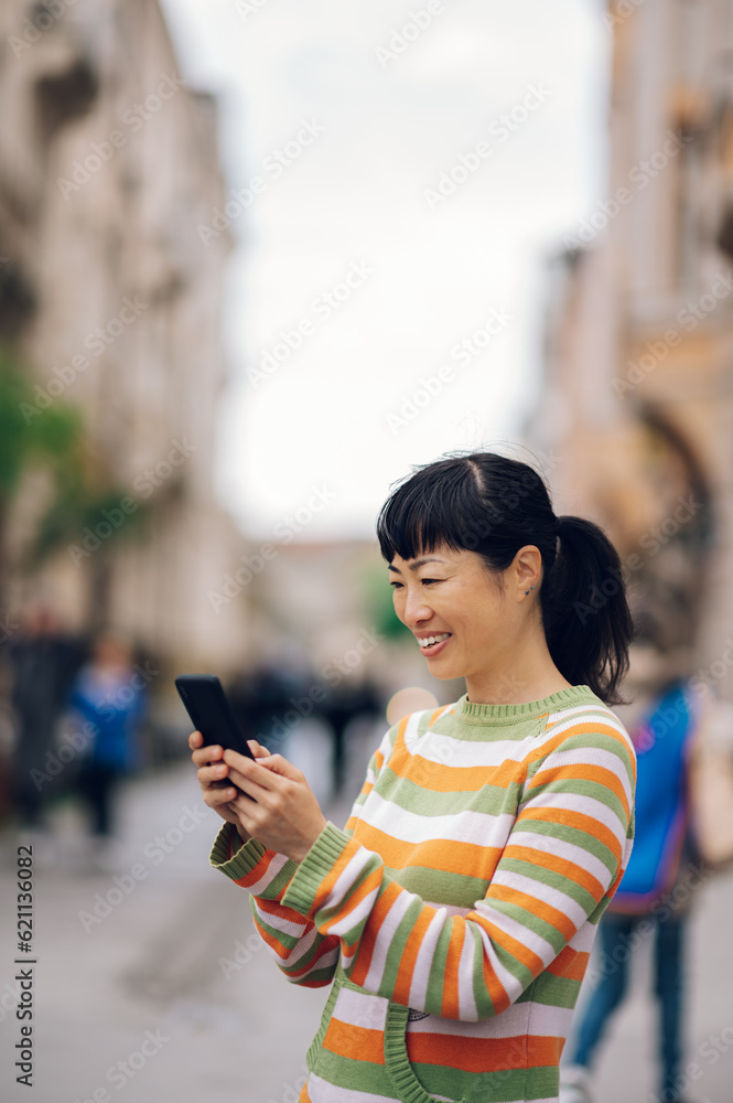 Fototapeta premium Joyful japanese girl enjoying a spring day while having an online video call.