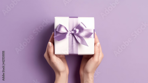 Female hands holding a purple gift box with a bow.