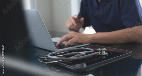 Fotografie, Tablou Close up of male doctor working and typing on laptop computer at doctor's office