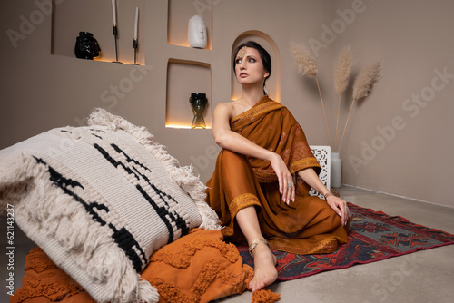 Canvas Print beautiful young woman sitting on the floor on a carpet in a traditional indian d