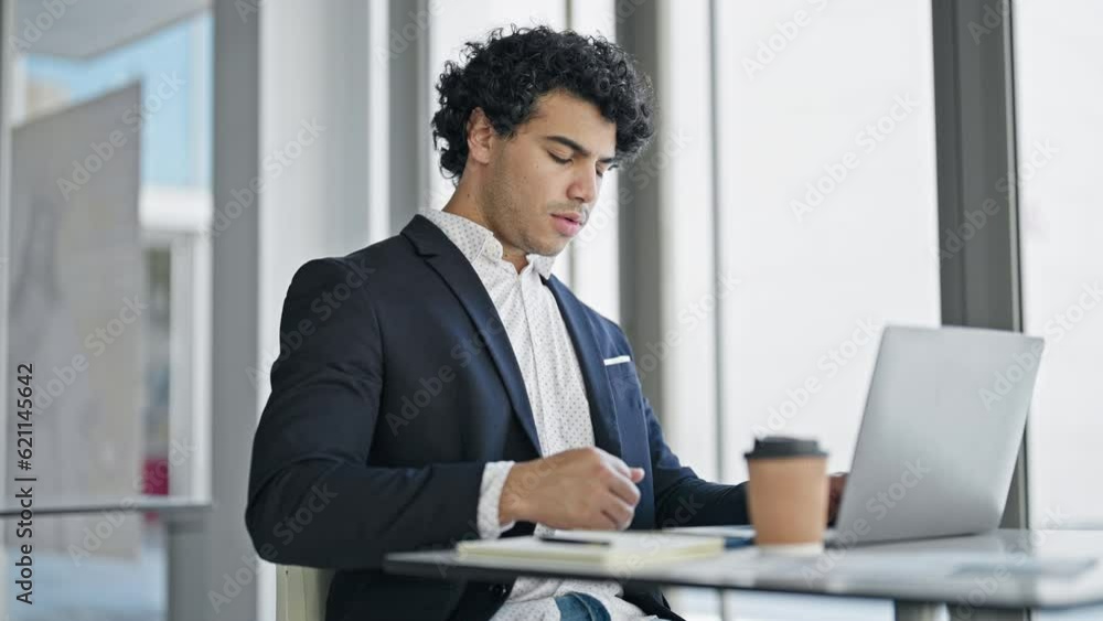 Young latin man business worker using laptop suffering for backache at office Young latin man business worker using laptop suffering for backache at office