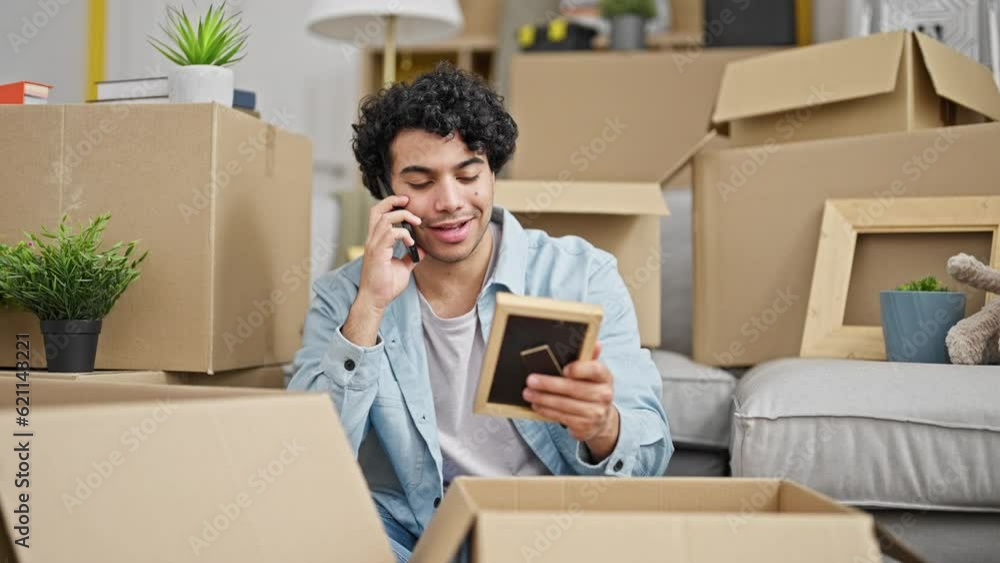 Young latin man talking on smartphone looking photo at new home Young latin man talking on smartphone looking photo at new home