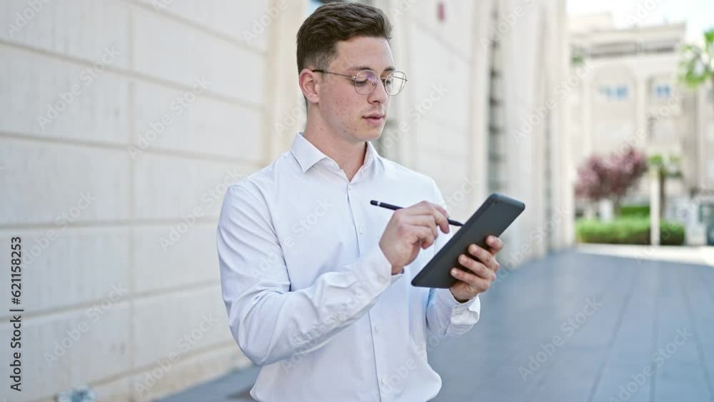 Young hispanic man business worker smiling confident writing on touchpad at street Young hispanic man business worker smiling confident writing on touchpad at street