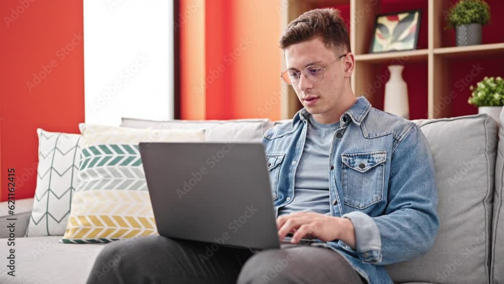 Young hispanic man using laptop sitting on sofa with stressed expression at home Young hispanic man using laptop sitting on sofa with stressed expression at home