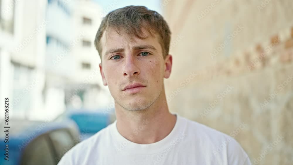 Young caucasian man standing with serious expression at street Young caucasian man standing with serious expression at street