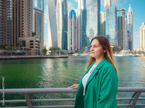 young woman in green suit walks streets of Dubai, Dubai Marina district. United Arab Emirates trip concept. the idea of successful expat, moving to another country, work visa