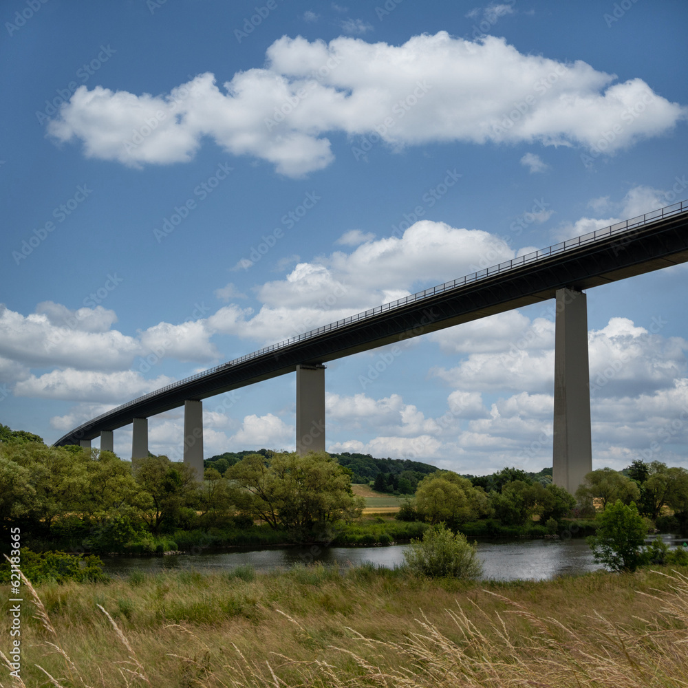 Blick auf eine Landschaft mit einer langen und hohen Brücke blauer Himmel weiße Wolken