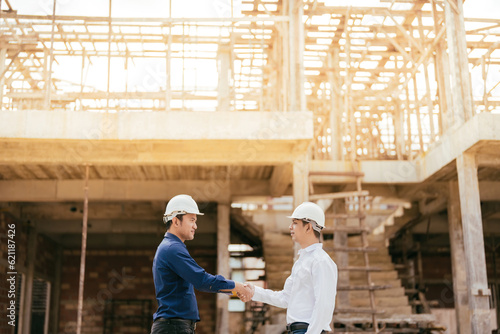 2 Asian male engineers are master technicians and supervisors. in construction design holding hands working together for success about the architecture industry Wear helmets and uniforms.