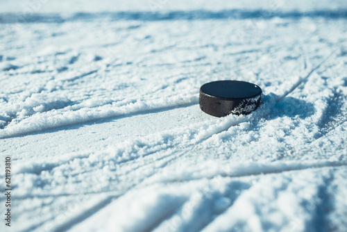 Photography hockey puck lies on the snow close-up
