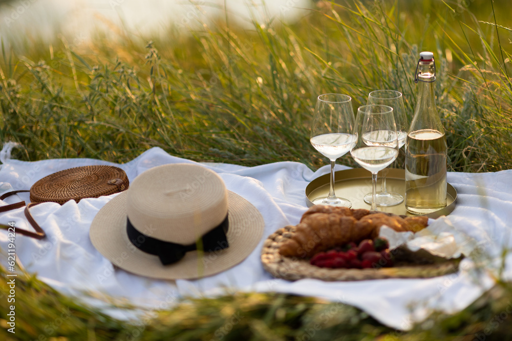 Romantic picnic with croissants, white wine and fresh berries in the mountain at sunny summer day.