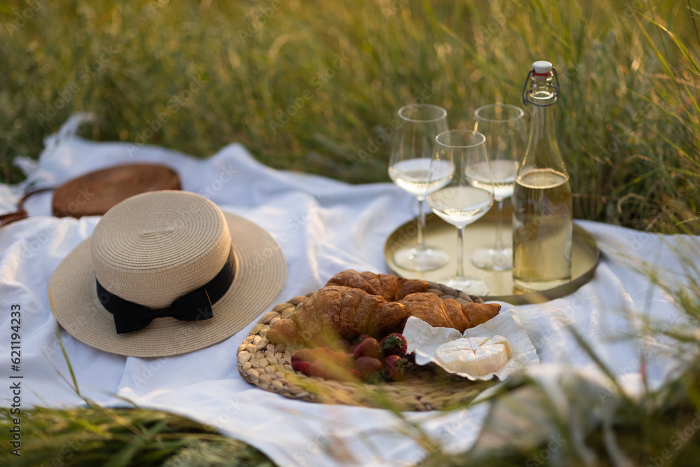 Beautiful summer picnic in the park with tasty fresh berries, croissants, cheese and wine. Pleasure time at nature.