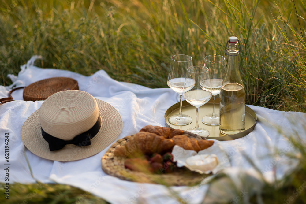 Set for romantic french picnic at nature. White wine, croissants and fresh berries on the green grass.