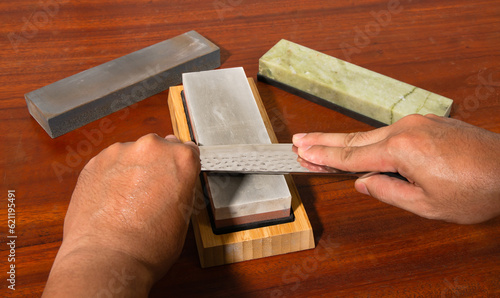 Craftsman sharpening knives on a Japanese whetstone, on a wooden table photo