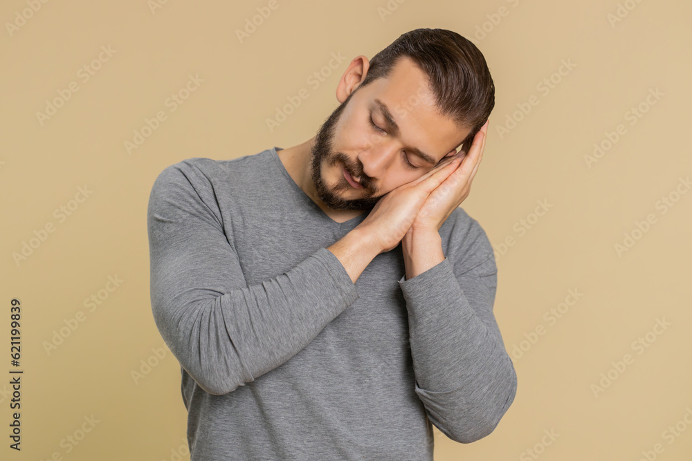 Tired overworked young lebanese man yawning sleepy inattentive feeling somnolent lazy bored gaping suffering from lack of sleep. Exhausted middle eastern guy isolated on studio beige background indoor Tired overworked young lebanese man yawning sleepy inattentive feeling somnolent lazy bored gaping suffering from lack of sleep. Exhausted middle eastern guy isolated on studio beige background indoor