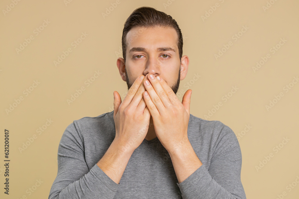 I will not say anyone. Frightened lebanese young man closing mouth with hand, looking intimidated scared at camera, gestures no, refusing to tell terrible secret unbelievable truth on beige background I will not say anyone. Frightened lebanese young man closing mouth with hand, looking intimidated scared at camera, gestures no, refusing to tell terrible secret unbelievable truth on beige background