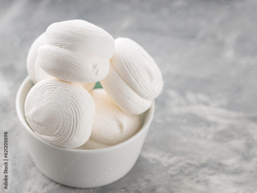 Fototapeta premium Zephyr marshmallows in bowl on a gray background. Sweet dessert marshmallows on concrete. Copy space