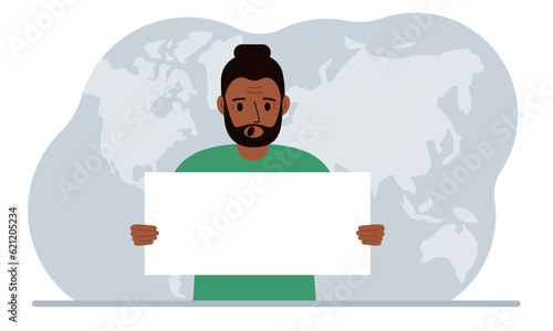 The concept of world attention. A man holds a white poster in his hands against the background of a world map.