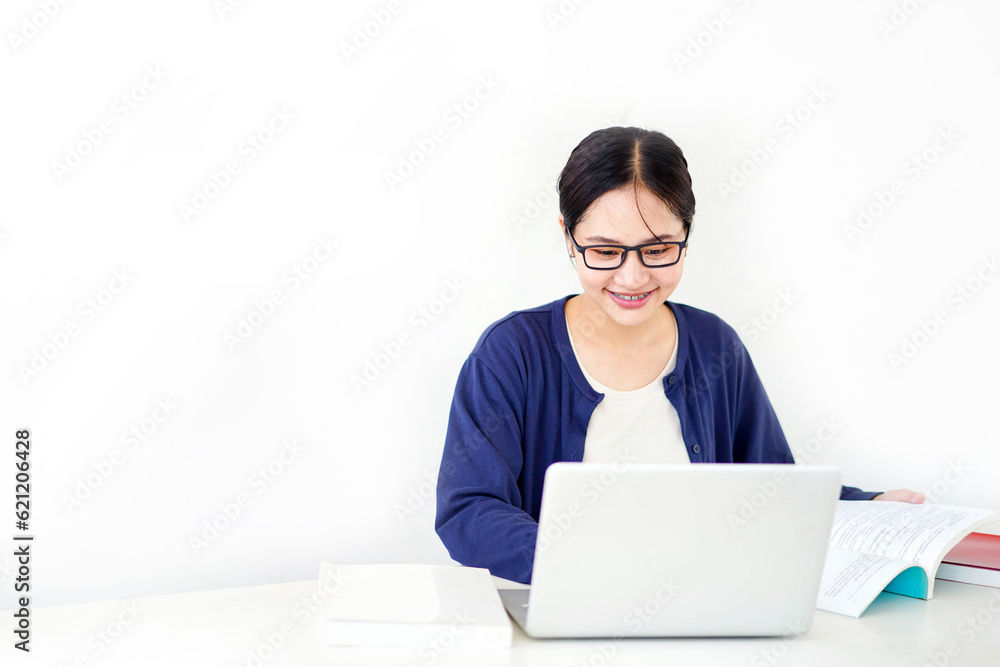 Closeup Asian young female student in casual cloth reading a textbook for the exam with laptop on white gradient background. Asian school concept.