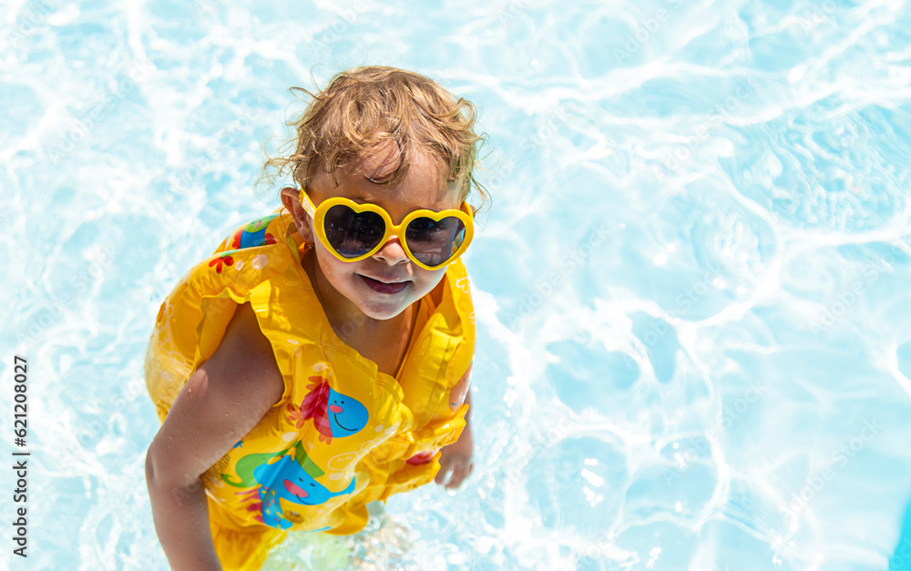 Naklejka premium The child swims in the pool in a vest. Selective focus.