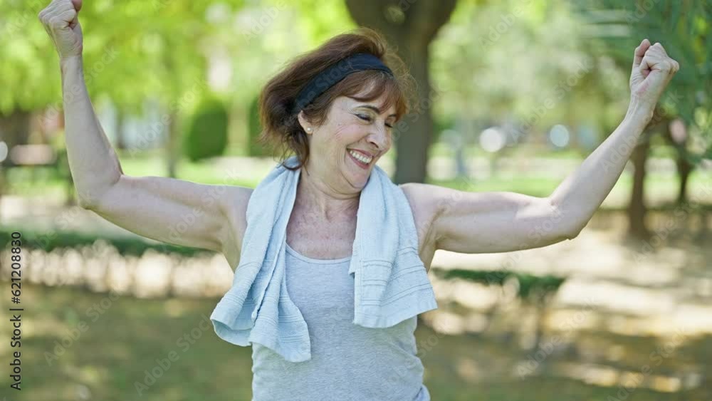 Middle age woman wearing sportswear doing strong gesture with arms at park Middle age woman wearing sportswear doing strong gesture with arms at park