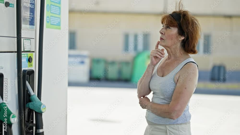 Middle age woman thinking at petrol station Middle age woman thinking at petrol station