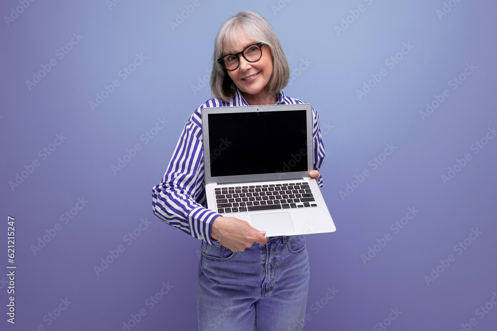 smiling 60s mature woman with gray hair with laptop mockup on bright studio background smiling 60s mature woman with gray hair with laptop mockup on bright studio background