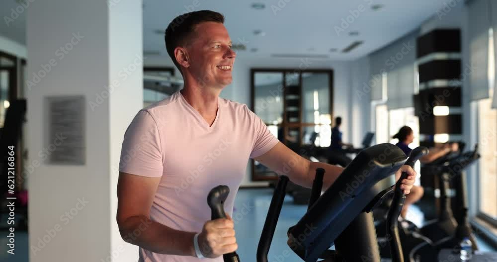 Man in gym goes in for sports on elliptical trainer. Healthy lifestyle and sport concept Man in gym goes in for sports on elliptical trainer. Healthy lifestyle and sport concept