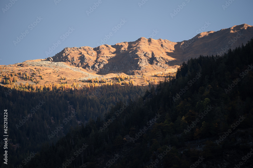 First morning light appearing over the peaks of mountains in the Poschiavo area in autumn, Switzerland