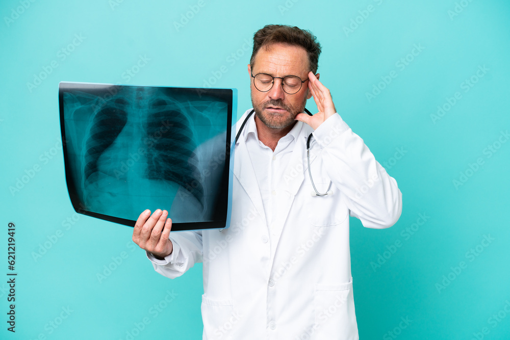 Middle age professional traumatologist doctor man isolated on blue background with headache Middle age professional traumatologist doctor man isolated on blue background with headache