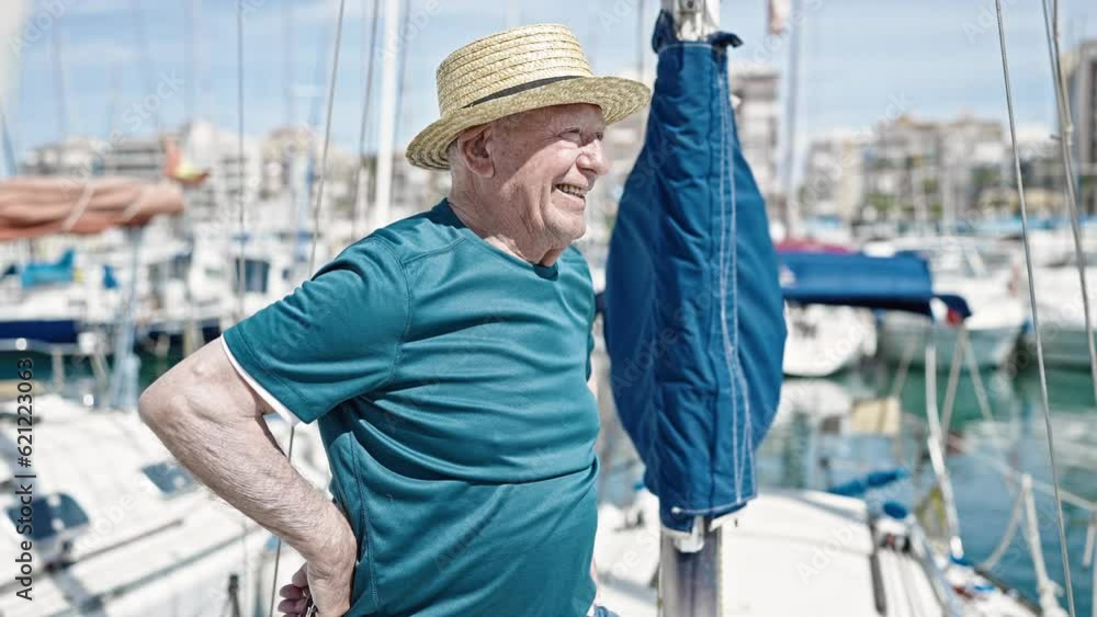 Senior grey-haired man tourist wearing summer hat smiling at boat Senior grey-haired man tourist wearing summer hat smiling at boat