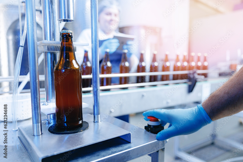 Workers work at brewery for production of craft beer. Bottling on conveyor, woman checks quality control of drink Workers work at brewery for production of craft beer. Bottling on conveyor, woman checks quality control of drink