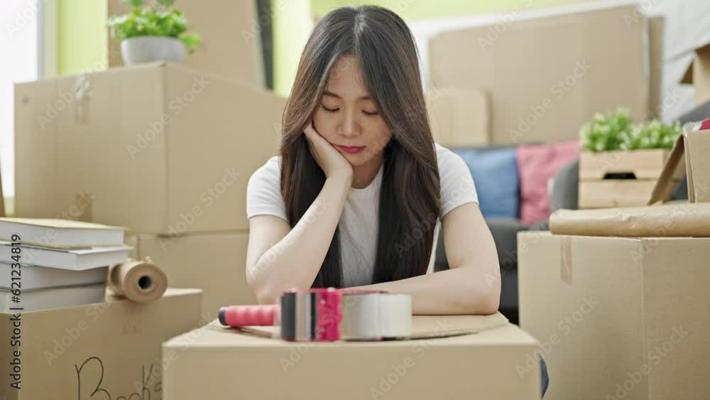 Young chinese woman sitting on floor with sad expression at new home Young chinese woman sitting on floor with sad expression at new home