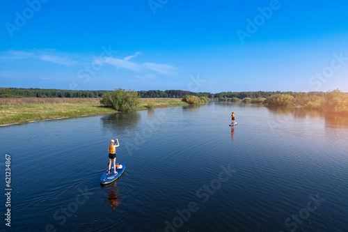 Active fun  Woman floats on river on supboard  sun light. Concept summer lifestyle sport for fun