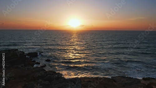 Aerial view over beautiful  ocean during  sunset. Top view to the ocean in summer day while sunset - closeup. Drone view of a Scenic slow motion ocean waves. Beautiful sunrise over ocean