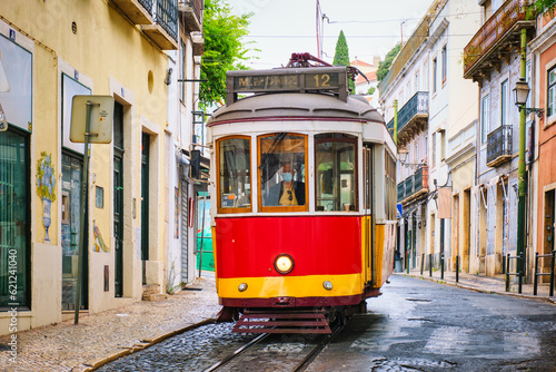 Famous vintage yellow tram in the narrow streets of Alfama district in Lisbon, Portugal - symbol of Lisbon, famous popular travel destination and tourist attraction