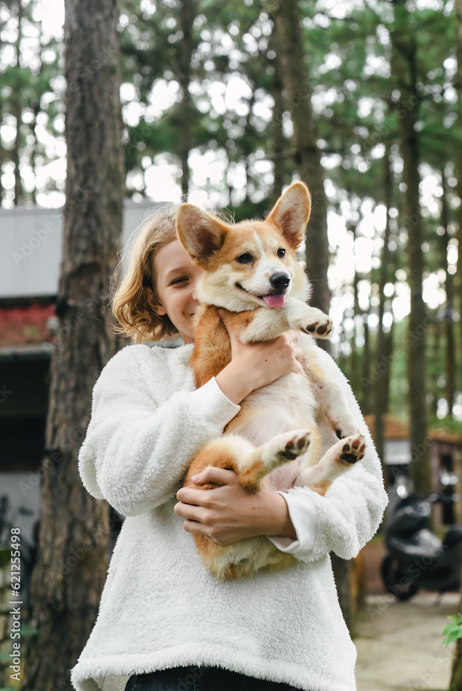 Little cute girl holding her corgi dog on an autumn day Little cute girl holding her corgi dog on an autumn day