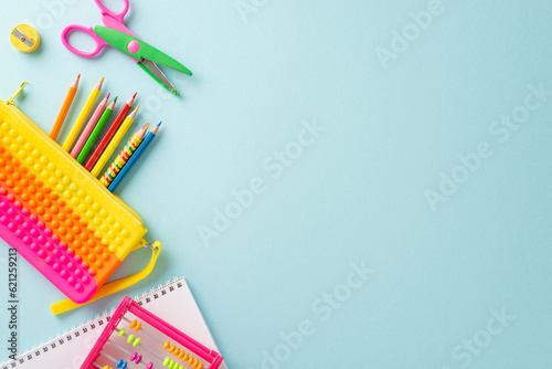 Immerse yourself in world of education for small kids with top view composition: lively collection of colorful school supplies on pastel blue surface, providing copyspace for text or advertisements