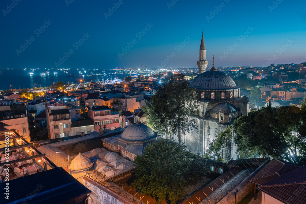 Night cityscape with buildings rooftop restaurant mosque minaret and lights in sea, Istanbul, Turkey