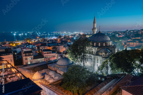 Night cityscape with buildings rooftop restaurant mosque minaret and lights in sea, Istanbul, Turkey