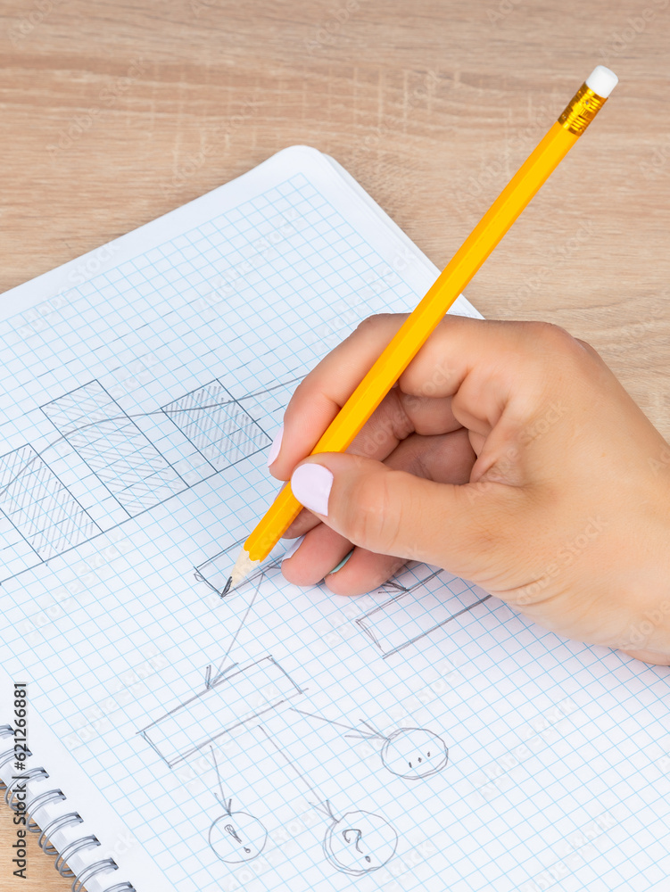 Close-up woman writes and draws a graph with a black slate pencil in a checkered notebook Close-up woman writes and draws a graph with a black slate pencil in a checkered notebook