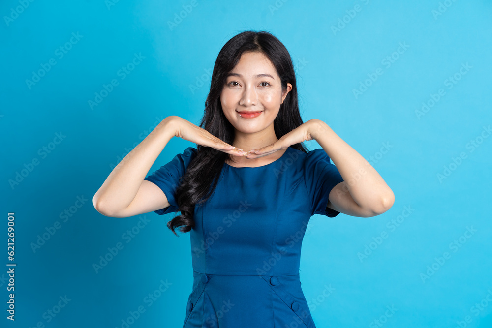 Fototapeta premium Portrait of beautiful woman in blue dress, isolated on blue background.